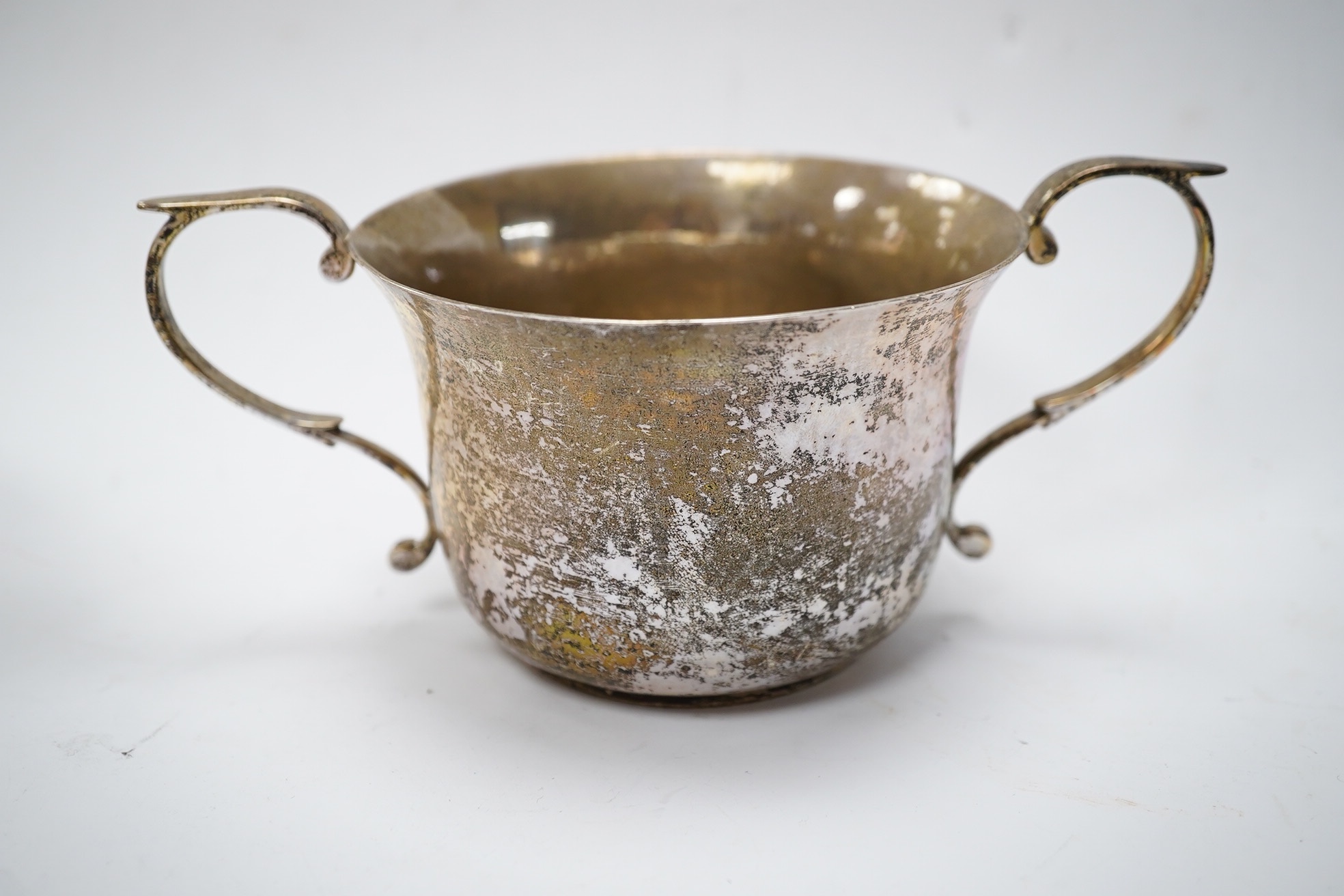 A George III Scottish silver cream jug, later embossed, a pair of George V silver sauce boats and an Edwardian hammered silver two handled porringer, by Moss Morris,18.4oz. Condition - poor to fair